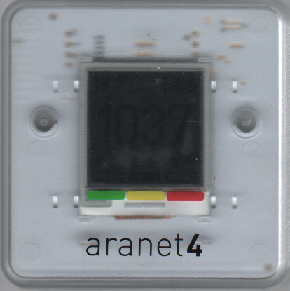 Scan of the front of an Aranet4 CO₂ monitor. The screen is black, although the number "1037" can faintly be made out.