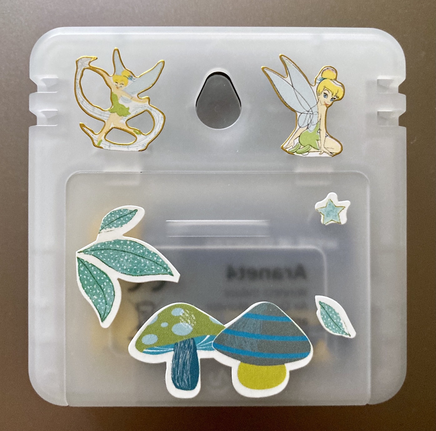 The back side of an Aranet4 device. The available space between the sensors and battery nook opening has been decorated with small stickers depicting Tinkerbell as well as various leaves and mushrooms.